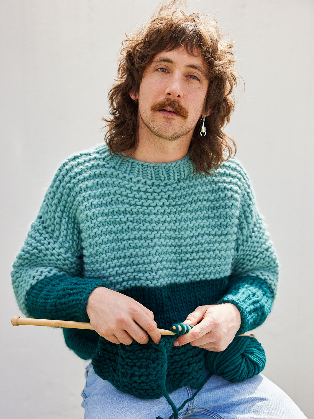 Man knitting wearing a chunky knitted jumper