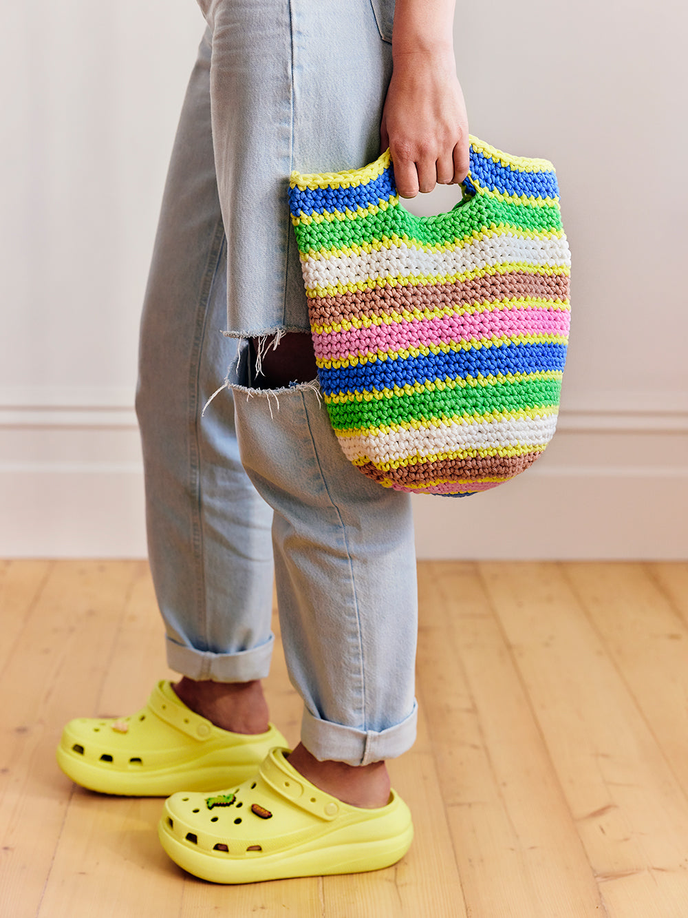 Photograph of person holding a brightly coloured stripey crochet bucket bag 