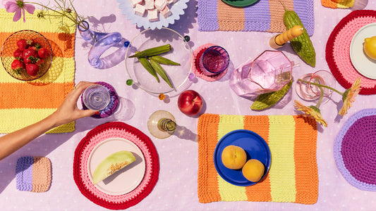 Birdseye view of colourful placemats and coasters, which fruit and vegetables.