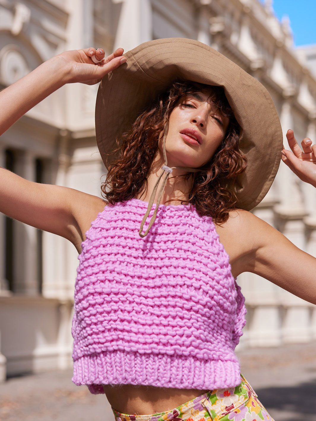 Girl in sun hat wearing a bright pink chunky knit top
