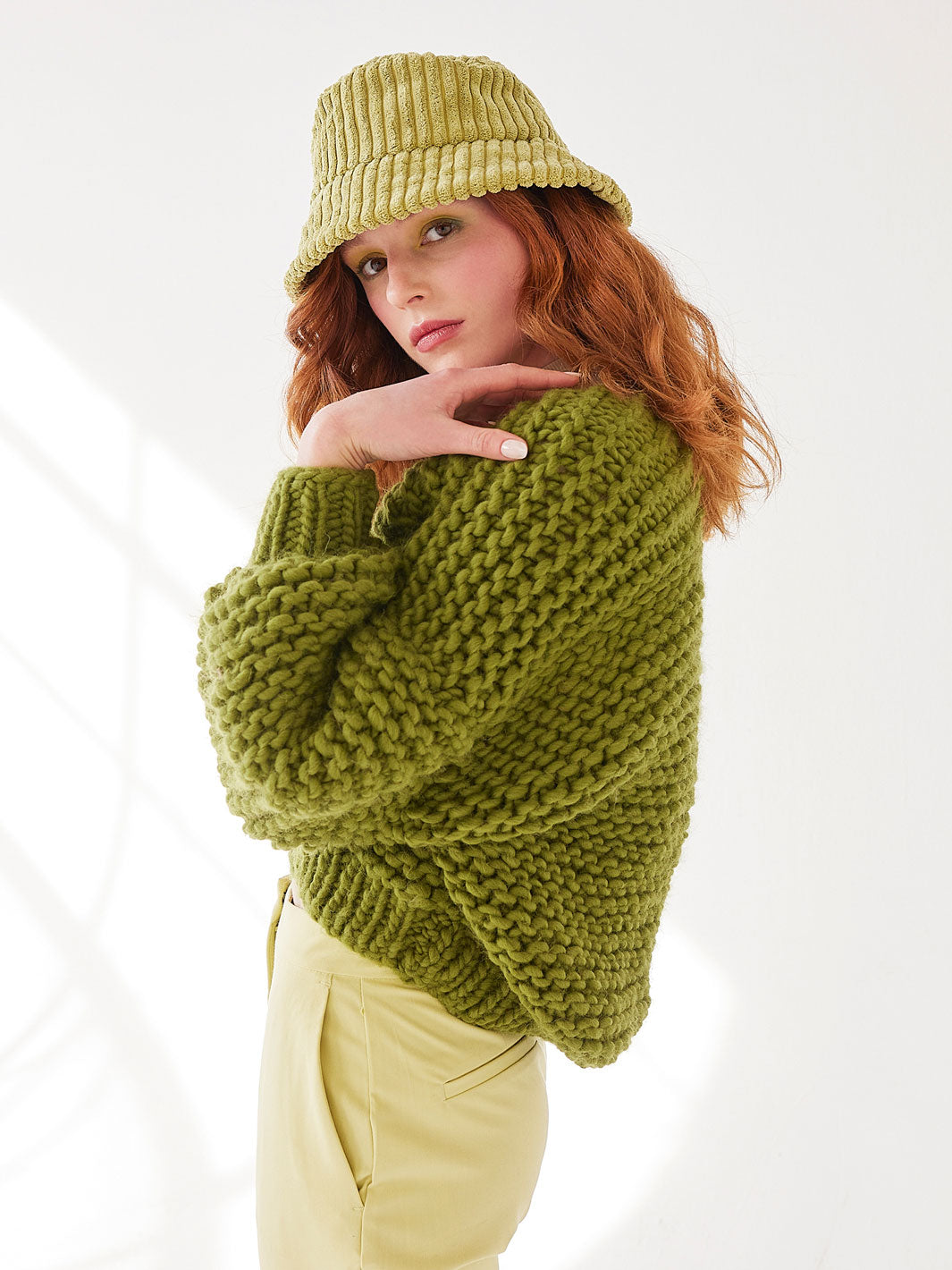 Girl in green hat wears a chunky knitted green cardigan