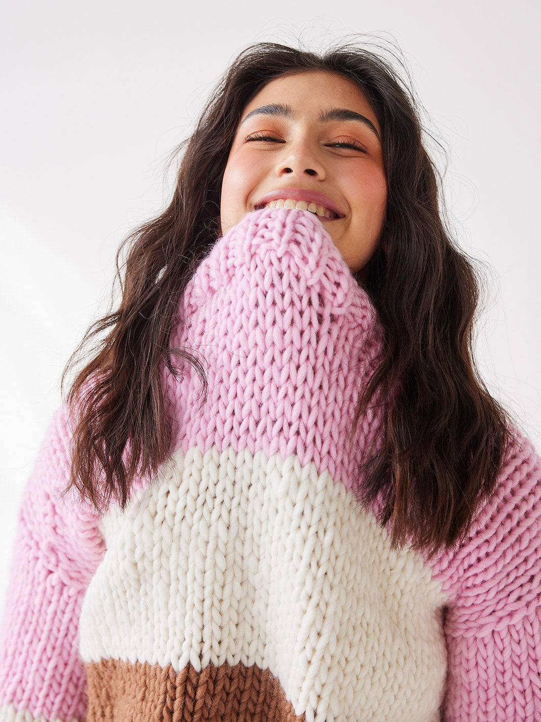 Girl looks at camera smiling with chunky knitted jumper 