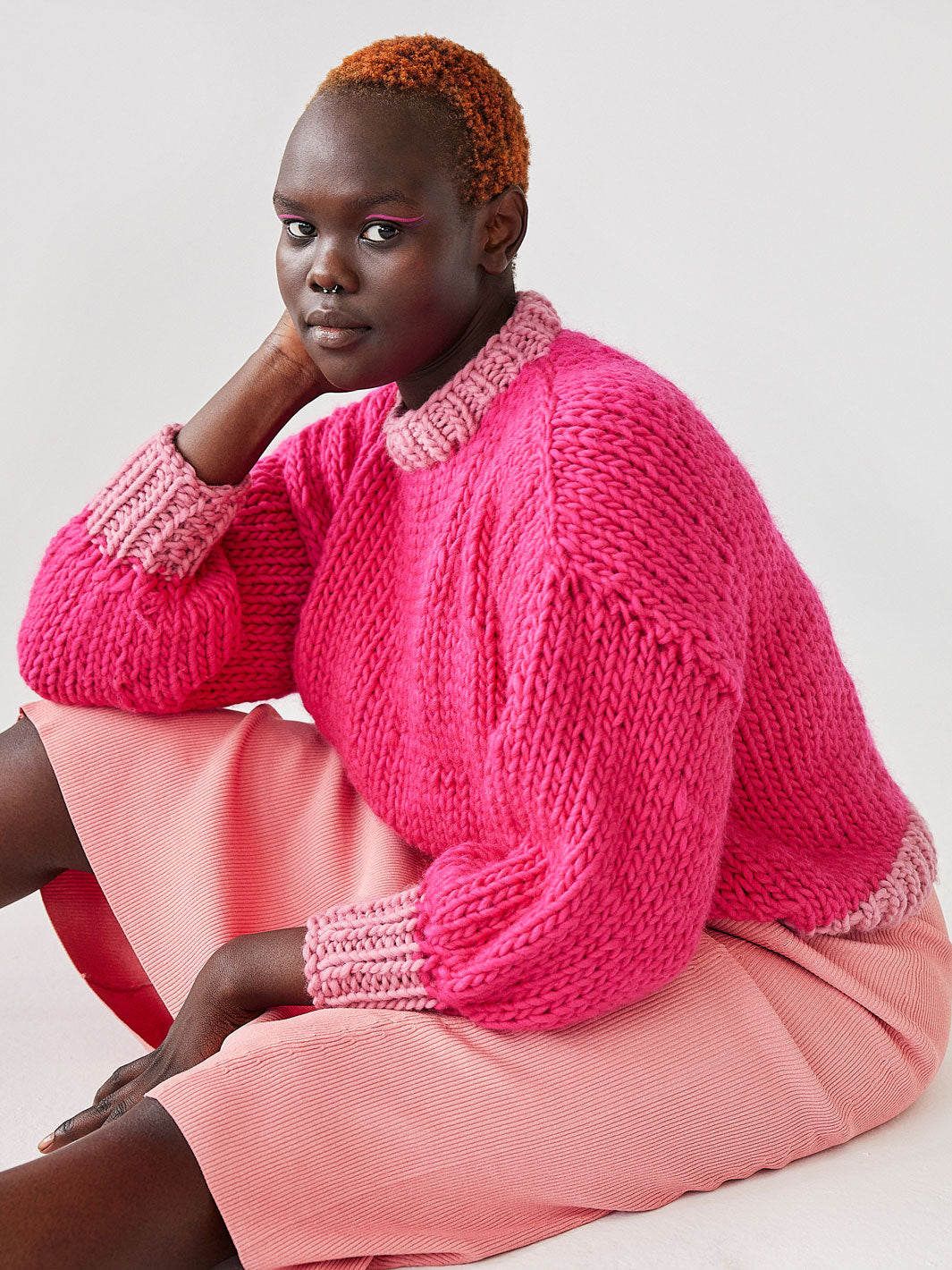 Girl sitting wearing bright chunky knit Betty jumper