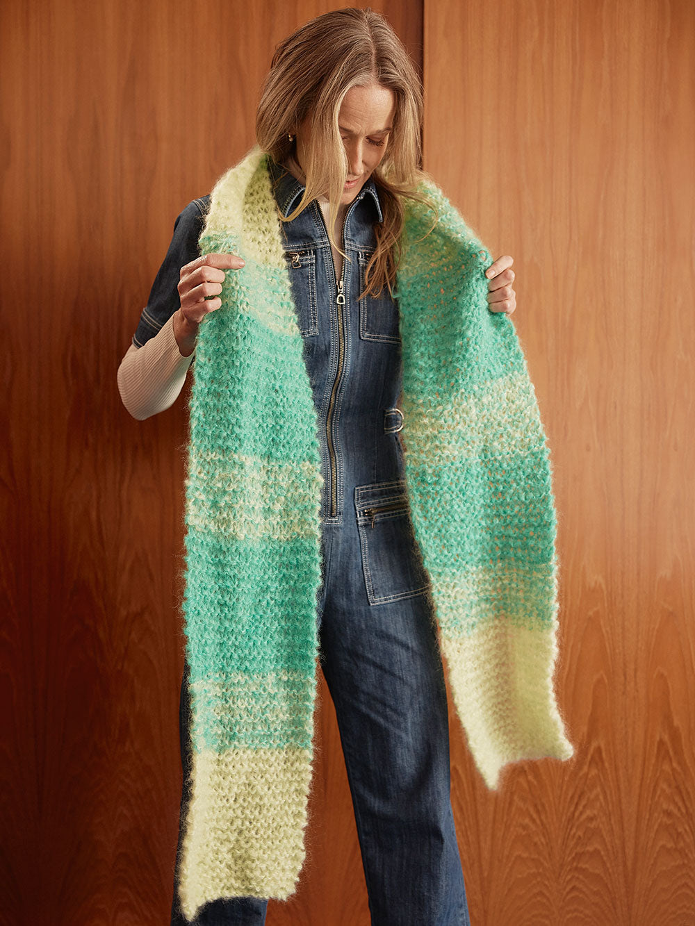 Woman stands in front of closet wearing a hand knitted mohair scarf