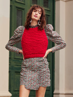 Girl with hands on hips wearing a red vest layered over dress