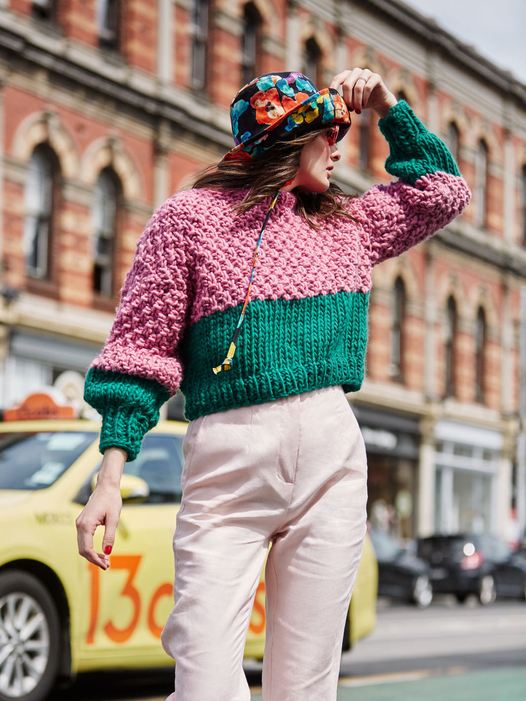 Girl wearing hat crosses a street in a chunky knitted jumper