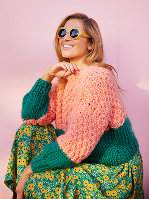 Girl in dress wears a chunky knitted jumper layered over the top 