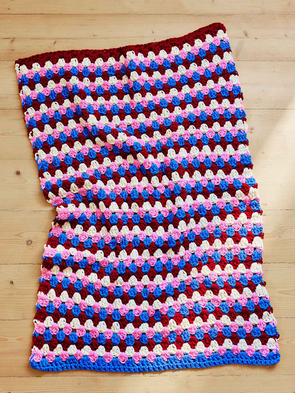 Picture of Margot Baby Blanket laying flat on floorboards.