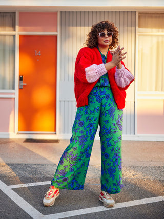 Girl stands in carpark parking lot wearing a bright red cardigan