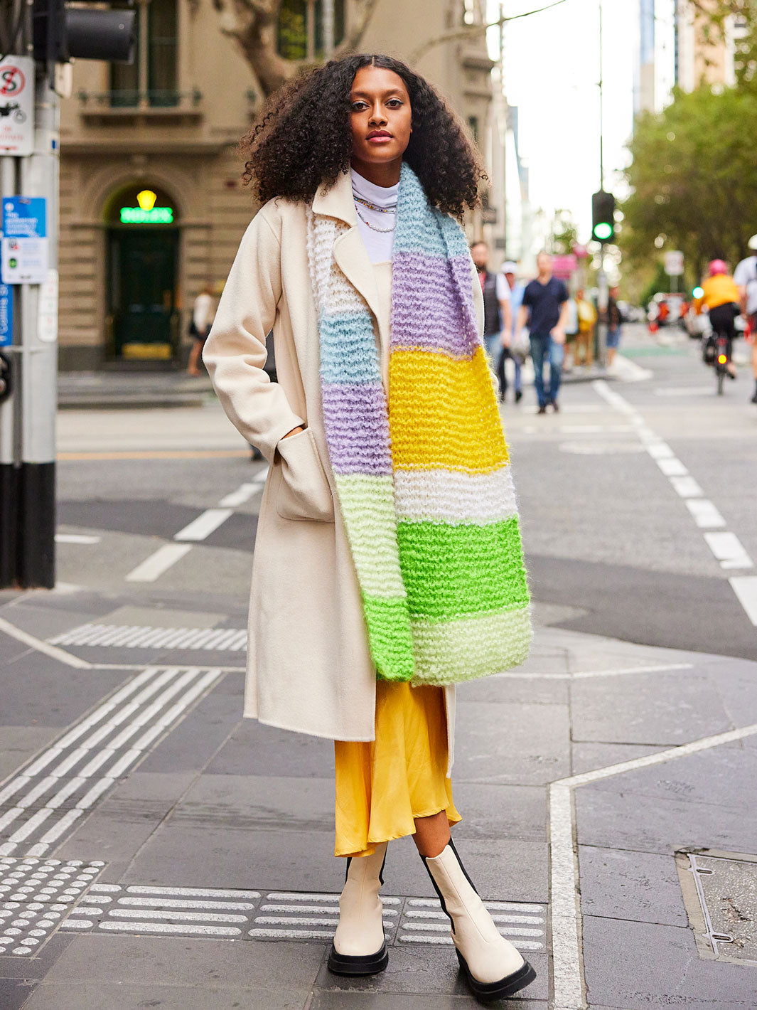 Woman stands at crossing wearing a colourful chunky knitted mohair scarf